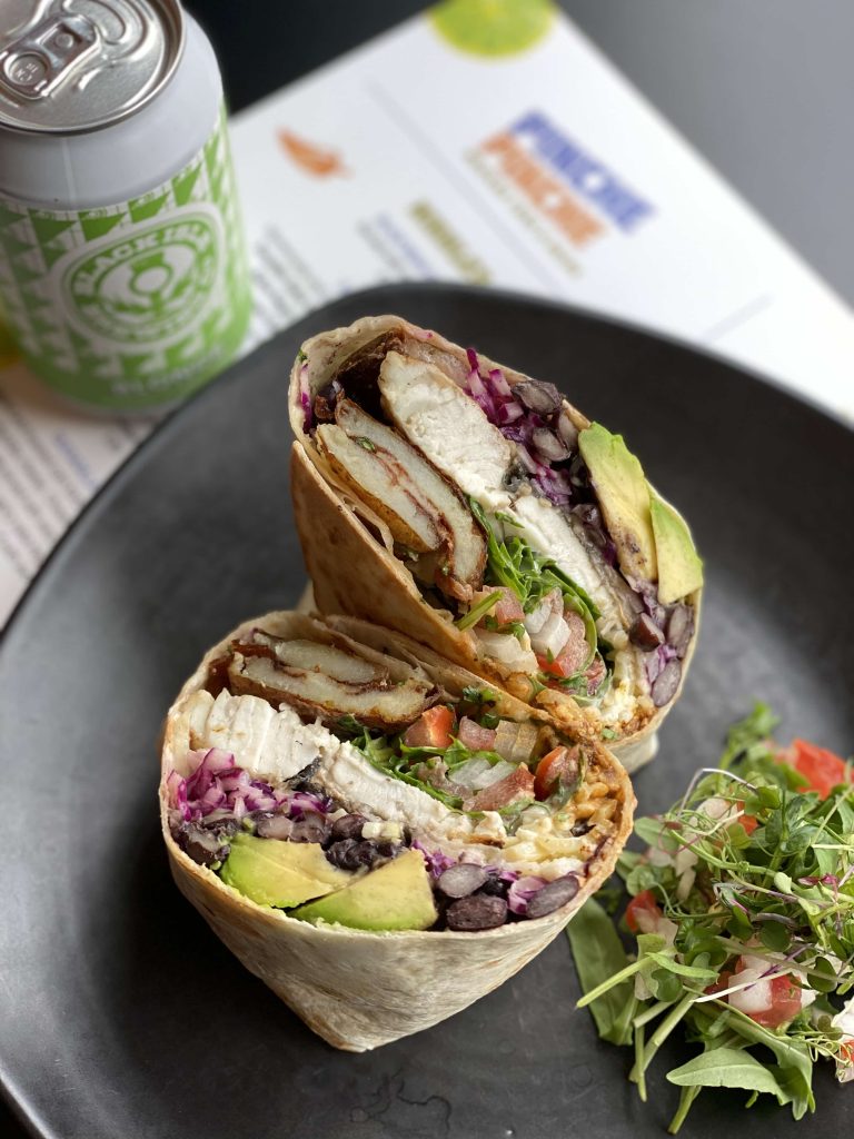 A picture showing a fish burrito with salad and a can of Blonde lager