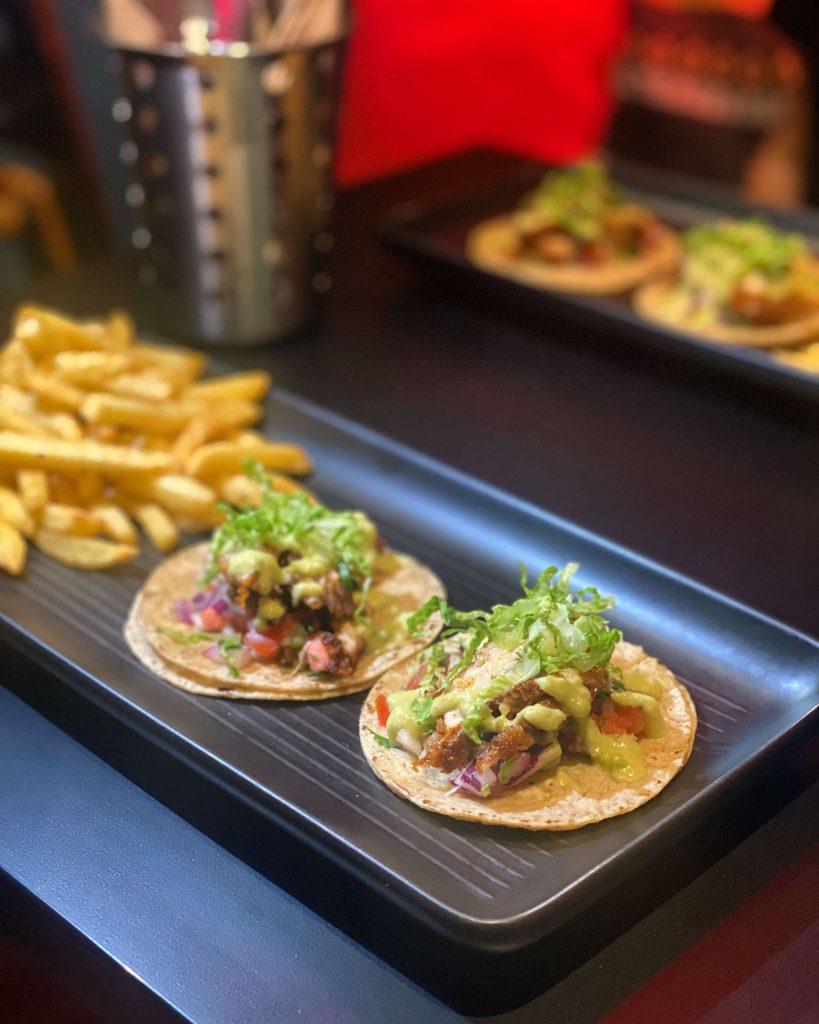 Picture showing a plate of tacos and Mexican fries on a table